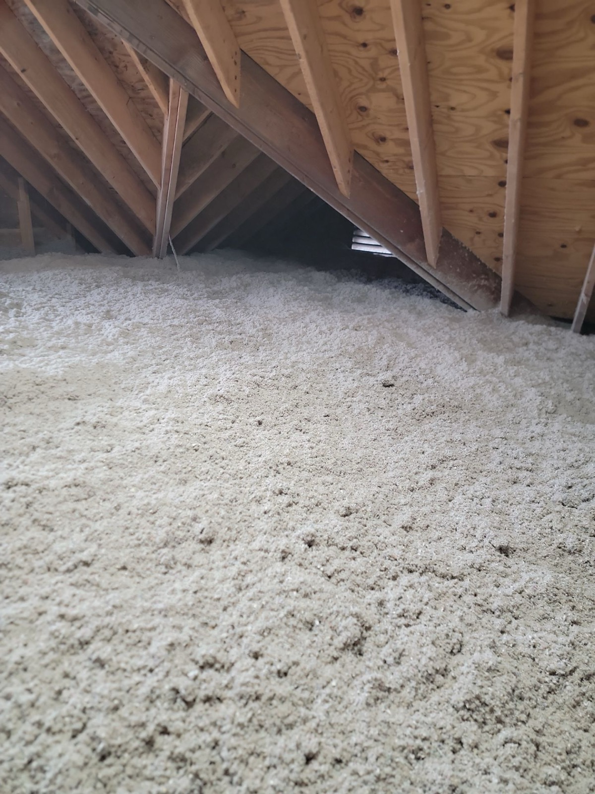 Poorly installed attic insulation with visible gaps and compressed batts in a Maine home