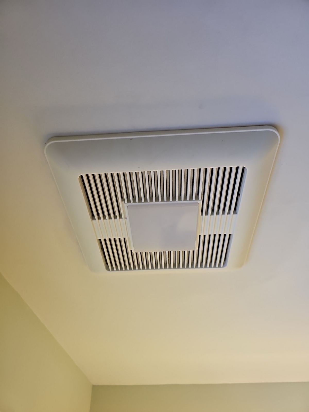 Bathroom exhaust fan installation in a Maine attic during an insulation retrofit project