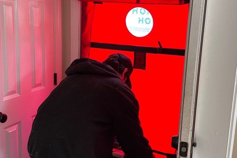 Horizon Homes crew member setting up a Minneapolis blower door test fan in a Maine home doorway