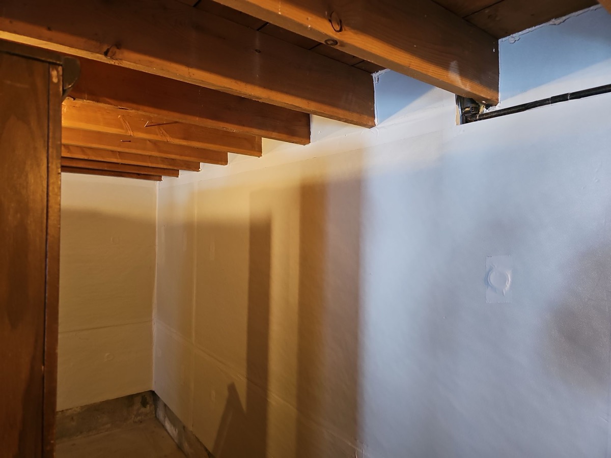 Unfinished Maine basement showing stone foundation walls and exposed floor joists