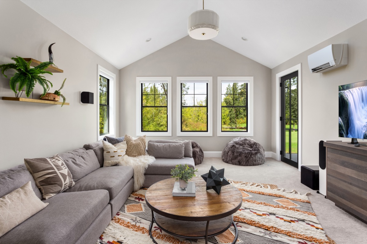 Bright modern Maine living room with vaulted ceiling, large windows, and a ductless heat pump mounted on the wall
