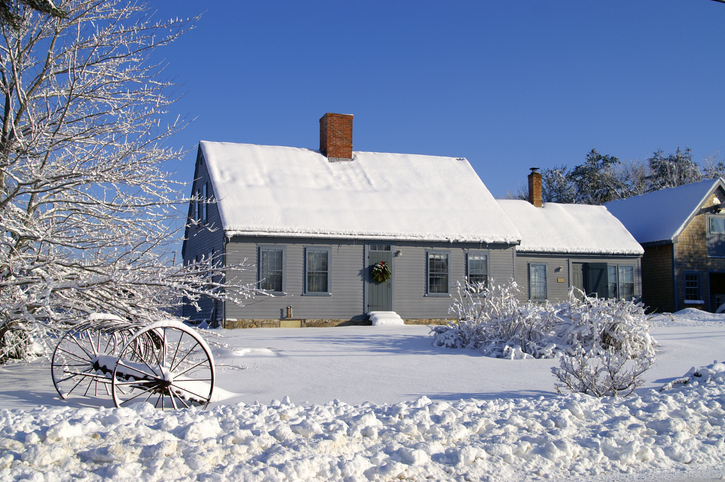 House covered in snow with two chimneys and many windows